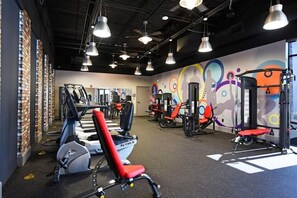 A gym with exercise equipment, a brick wall, and a colorful mural. - Spacious 3-bedroom townhome in lovely Davenport with AC (Davenport)