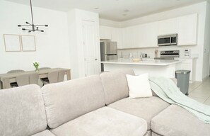 A modern kitchen with white cabinetry, a central island, and stainless steel appliances. - Spacious 3-bedroom townhome in lovely Davenport with AC (Davenport)
