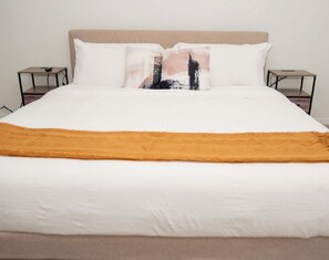 A bed with a white mattress, a beige headboard, and two bedside tables with a single book on each. - Spacious 3-bedroom townhome in lovely Davenport with AC (Davenport)
