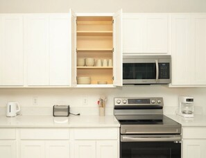 A kitchen with white cabinets, a microwave, an oven, a toaster, and a coffee maker. - Spacious 3-bedroom townhome in lovely Davenport with AC (Davenport)