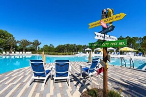 A poolside area with lounge chairs and a signpost indicating distances to various cities. - Spacious 3-bedroom townhome in lovely Davenport with AC (Davenport)