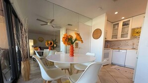 A modern dining area with a round table, white chairs, and a vase of sunflowers. - Big Beautiful Bed, View and Balcony! (Palm Springs)