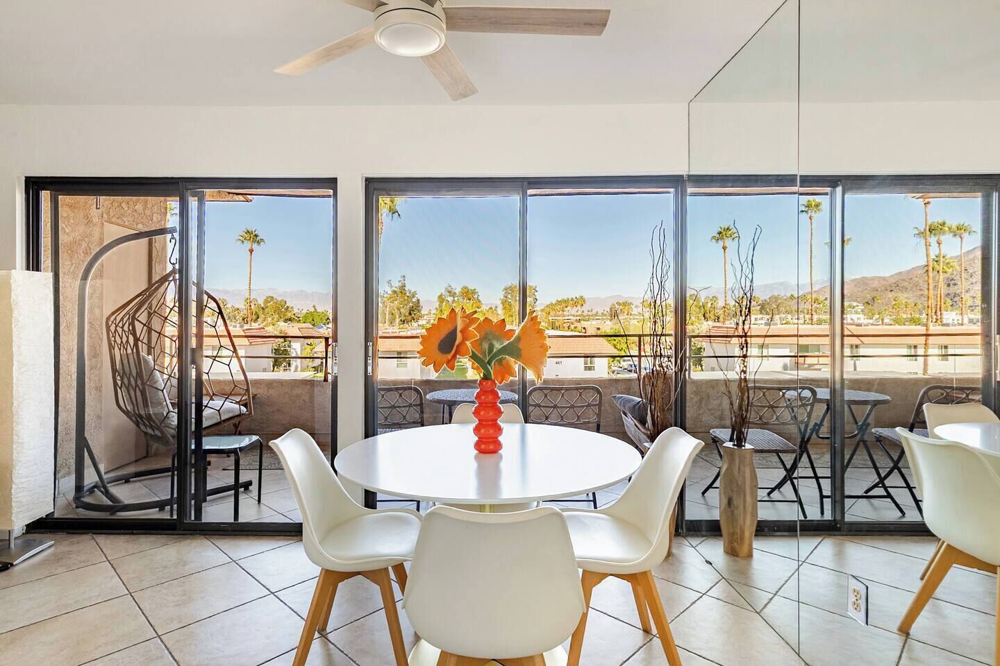 Un coin repas avec une table ronde, des chaises blanches et un vase de fleurs.