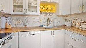 A kitchen with white cabinets, a yellow backsplash, and a marble tile wall. - Big Beautiful Bed, View and Balcony! (Palm Springs)