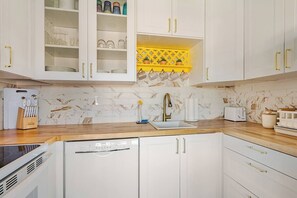 A kitchen with white cabinets, a yellow backsplash, and a marble tile wall. - Big Beautiful Bed, View and Balcony! (Palm Springs)