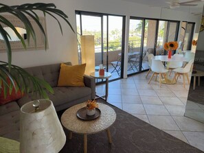 A living room with a sofa, a round coffee table, and a dining area with chairs and a table. - Big Beautiful Bed, View and Balcony! (Palm Springs)