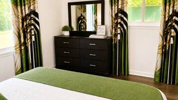 Une chambre à coucher comprenant un lit, une commode, un miroir et des rideaux à motifs de feuilles.