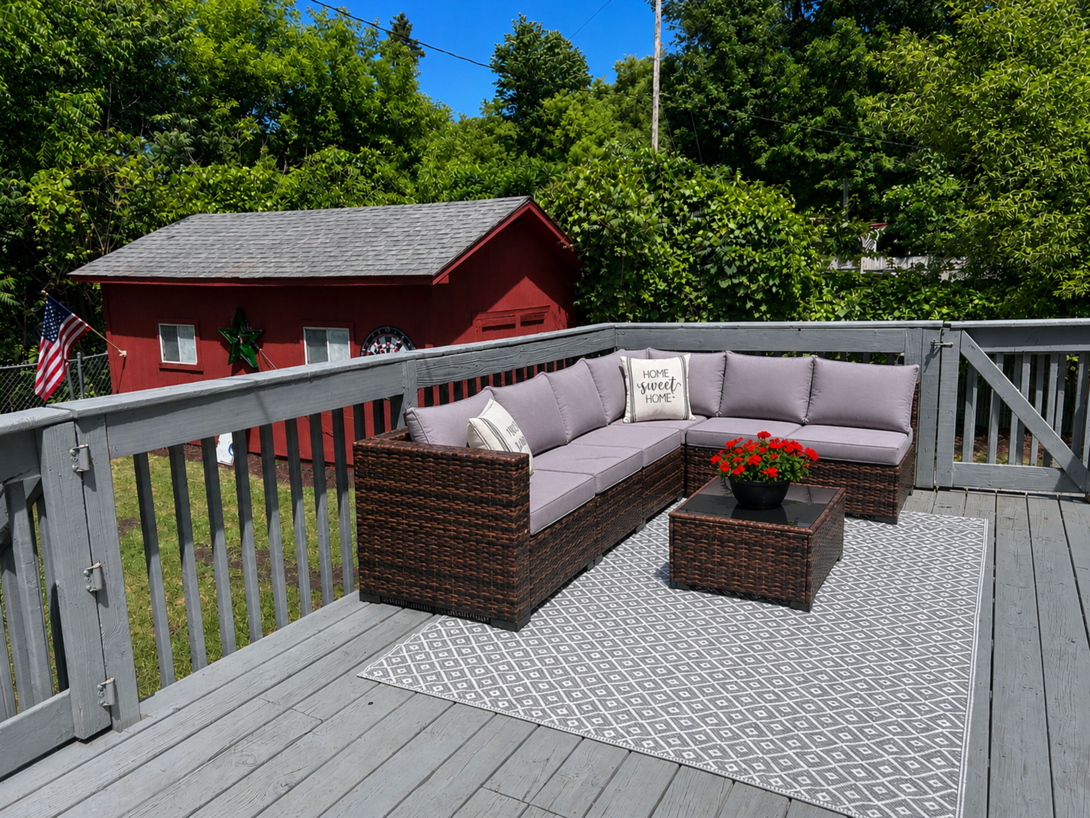 Une terrasse avec un canapé en osier, une table basse et un tapis à motifs.