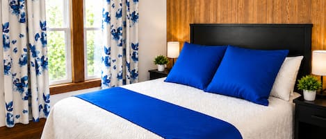 A bedroom with a large bed, wooden headboard, two bedside lamps, and a window with curtains.