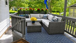 A covered porch with a sofa, a small table, and a potted plant.