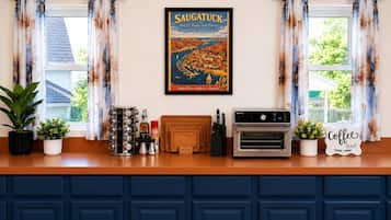Een keukenblad met een bordje koffiebar, een vintage oven en een poster van Saugatuck.