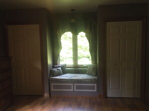 A room with a built-in bench under a window, a door, and a ceiling light fixture.