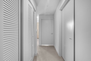 A hallway with white walls and doors, leading to a room. - Luxury 2BR | Downtown Miami Near Worldcenter (Miami)