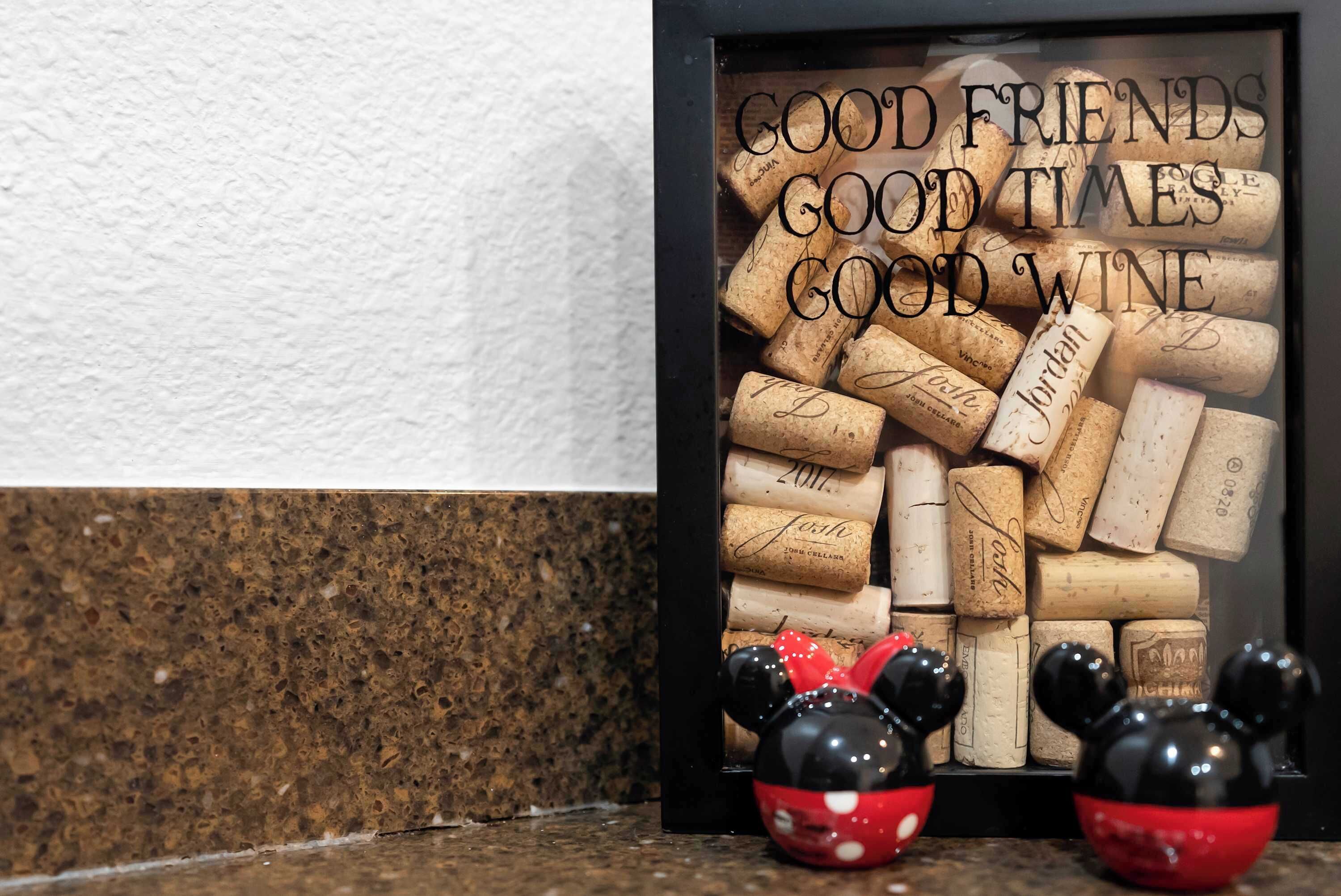 A corkboard with wine corks and a sign that reads 'GOOD FRIENDS GOOD TIMES GOOD WINE.'