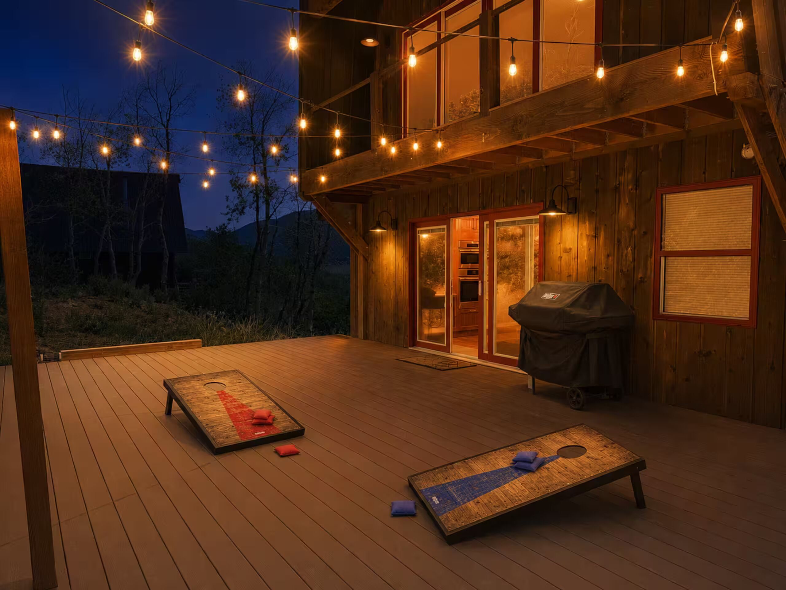 A wooden deck with string lights, a grill, and a shuffleboard table.