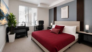 Um quarto moderno com uma cama grande, uma escrivaninha, uma cadeira e um vaso de plantas.