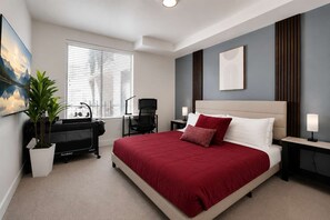 Ein modernes Schlafzimmer mit einem großen Bett, einem Schreibtisch, einem Stuhl und einer Topfpflanze.