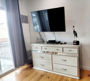 Una stanza con una cassettiera bianca, una TV a schermo piatto montata a parete e una statuetta decorativa a forma di uccello sopra.