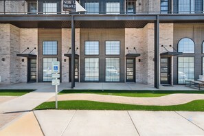 Un bâtiment à la façade en briques, doté de grandes fenêtres et d’un panneau indiquant des places de stationnement réservées.