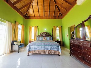 A bedroom with a wooden ceiling, a bed with a patterned bedspread, a dresser, and a chair. - Natutre Escape Oceanview Oasis   (Hopewell)