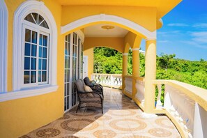 A covered outdoor area with a yellow wall, a white balustrade, and a tiled floor. - Natutre Escape Oceanview Oasis   (Hopewell)