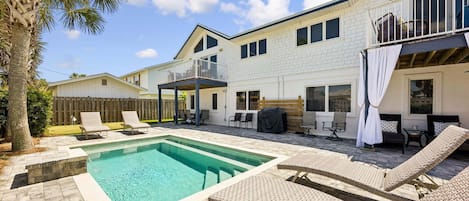 A two-story house with a swimming pool, outdoor seating, and a wooden deck.