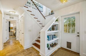 Un escalier avec une rampe blanche et des marches en bois menant à un palier où se trouve une bibliothèque.