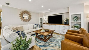 Een moderne woonkamer met een bank, salontafel en fauteuils.