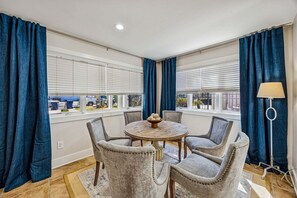 A room with a round table and four chairs, large windows with blinds, and blue curtains. - Renovated and Spacious 6BR duplex on Amelia Island near the beach with pool (Fernandina Beach)