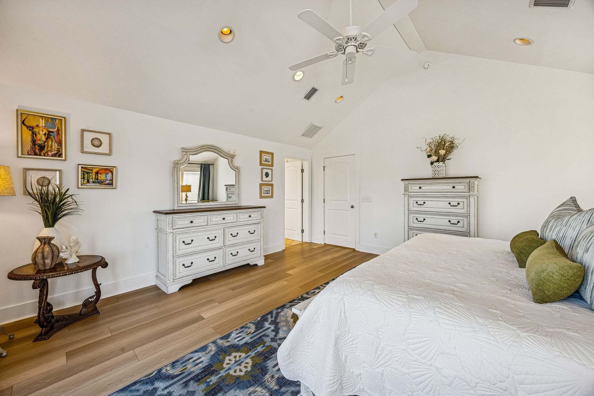Un dormitorio con una cama grande, ventilador de techo, cómoda y espejo.