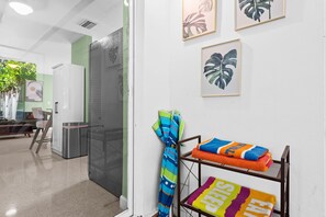 A hotel room with a kitchenette, a glass door leading to a balcony, and a wall with framed artwork. - Sunny 2BR Apartment w/ Private Backyard & Hot Tub (Wilton Manors)