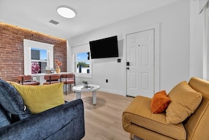 Ein Wohnzimmer mit einer Couch, einem Couchtisch und einem an der Wand befestigten Fernseher.