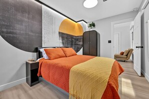 Un dormitorio moderno con una cama grande, un armario, una mesita de noche y una silla.