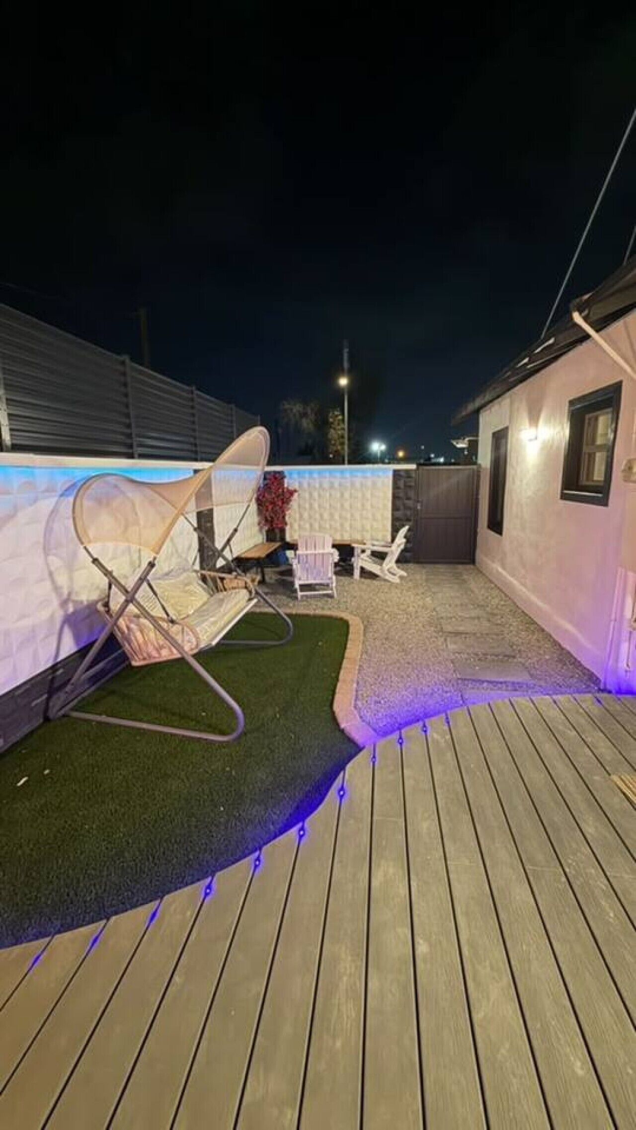A deck with a cushioned seating area, a small garden, and a lighted pathway.
