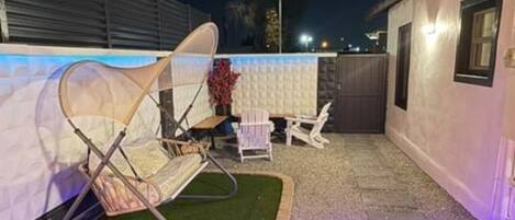 A deck with a cushioned seating area, a small garden, and a lighted pathway.