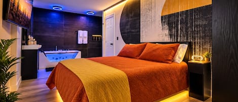 A modern bedroom with a large bed, a wall-mounted TV, and a bathroom with a bathtub.