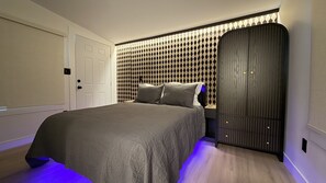 A bedroom with a bed, a wardrobe, and a patterned wall. - Elara | Sauna & Cold Plunge Retreat (Phoenix)