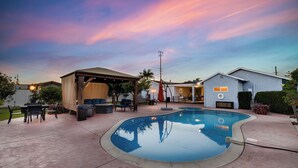 Um quintal com piscina, área de estar externa e um espaço coberto de varanda.