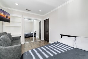 Ein Hotelzimmer mit Bett, einer Sitzecke, einem Fernseher und einer Schiebetür zu einem Badezimmer.