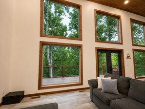 A room with large windows, a gray sofa, and a wooden ceiling. - Beautiful Views in Gatlinburg's Art District (Gatlinburg)