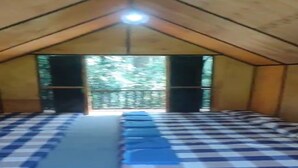 A room with a checkered floor, a row of blue chairs, and a view of trees through a doorway. - Cozzy Taman Nyingkur (bandung)