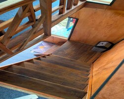 Una escalera de madera que sube a un piso superior con vistas al exterior.