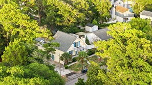 Ett bostadsområde med ett hus som har en balkong och som är omgivet av frodiga, gröna träd.
