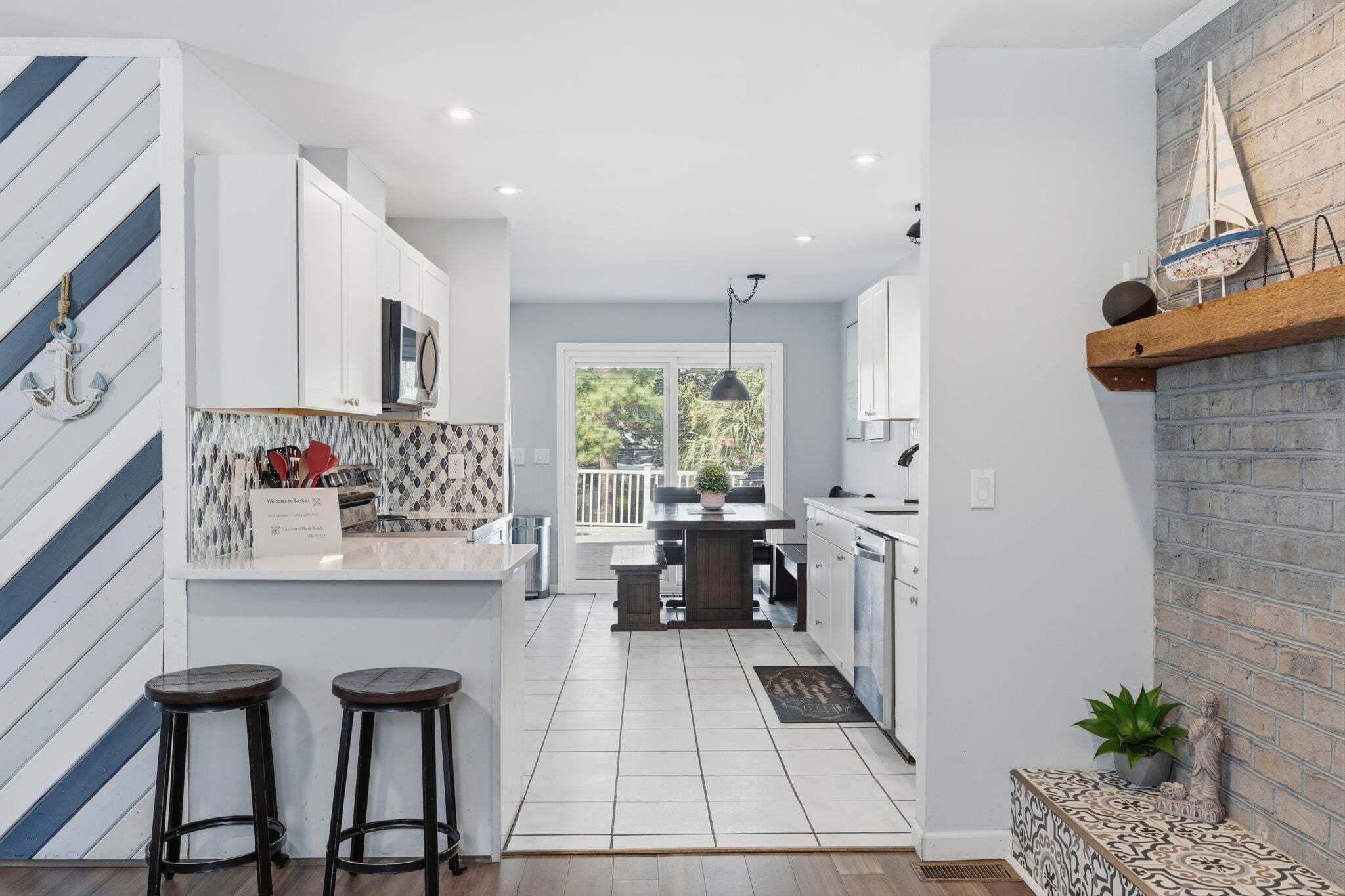 A modern kitchen with white cabinetry, a central island, and a view to the outdoors.