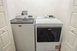 Two Maytag front-loading washing machines in a laundry room with white walls and doors.