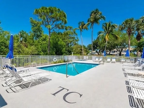 A swimming pool area with lounge chairs and umbrellas, surrounded by palm trees and a clear sky. - Luxury3BRNaplesCondo-Optional Club Membership- Beach Shuttle to Wiggins pass (Naples)