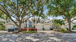 A residential area with multiple houses, a parked car, and well-maintained landscaping. - Luxury3BRNaplesCondo-Optional Club Membership- Beach Shuttle to Wiggins pass (Naples)