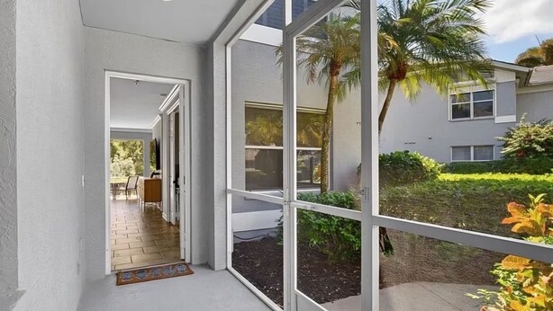 A corridor with a view of a garden and a building. - Luxury3BRNaplesCondo-Optional Club Membership- Beach Shuttle to Wiggins pass (Naples)