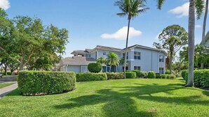 A two-story residential building with a well-maintained lawn and palm trees. - Luxury3BRNaplesCondo-Optional Club Membership- Beach Shuttle to Wiggins pass (Naples)