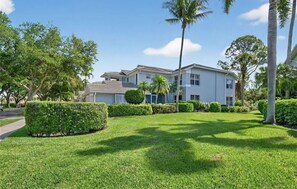 A two-story residential building with a well-maintained lawn and palm trees. - Luxury3BRNaplesCondo-Optional Club Membership- Beach Shuttle to Wiggins pass (Naples)